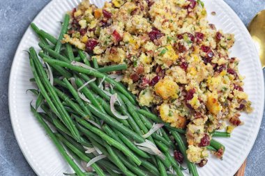 Karamelli arpacık soğanı ve geleneksel kızılcık cevizli mısır ekmeği soslu yeşil fasulye, klasik Yeni Yıl arifesi yemeği için garnitür, yatay üst manzara.