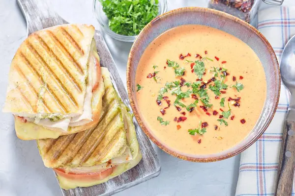 Kavanozda kırmızı biber kremalı çorba, ızgara hindi panini, dikey ızgara hindi panini, yatay üst görünüm.