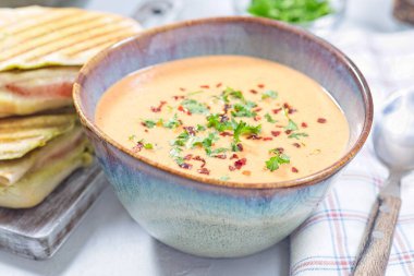 Kırmızı çan biberi kremalı çorba, ızgara hindi panini, yatay yakın plan.