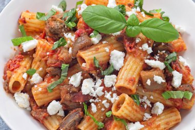 Rigatoni, patlıcan ve taze fesleğen ve ricotta salata peyniriyle kaplanmış zengin domates sosuyla yapılmış lezzetli bir makarna.