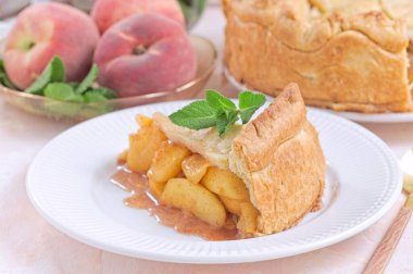 Ev yapımı eski moda şeftali turtası, taze nane ile süslenmiş, mükemmel bir yaz tatlısı, beyaz bir tabakta, yatay