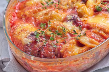 Fırında tatlı patates, havuç ve pancar kökü graten, taze kekik ile baharatlı ve erimiş peynirle kaplı, yatay yakın plan.