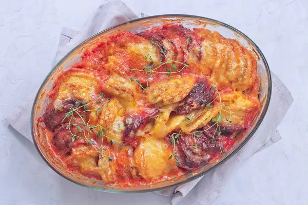 Fırında pişmiş tatlı patates, havuç ve pancar kökü graten, taze kekik ile tatlandırılmış ve üzerinde erimiş peynir, yatay üst görünüm