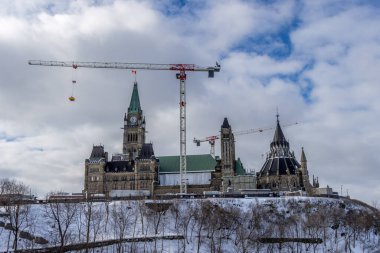 Having a walk through the Majors Hill Park in downtown Ottawa Canada with view to the historical buildings of the Canadian parliament and its surroundings at a cold but sunny day in winter.