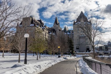 Having a walk through the Majors Hill Park in downtown Ottawa Canada with view to the historical buildings of the Canadian parliament and its surroundings at a cold but sunny day in winter.