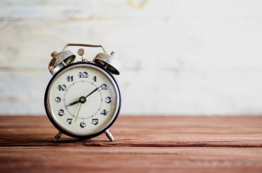 alarm clock on wooden table with vintage tone