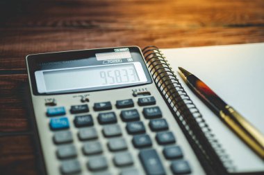 Tahta bir arka planda hesap makinesi, kalem ve defter. Manzarayı kapat. İş, finans, eğitim kavramı