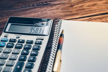Hesap makinesini, kalemini ve defterini ahşap arka planda kapat. İş, finans, eğitim kavramı