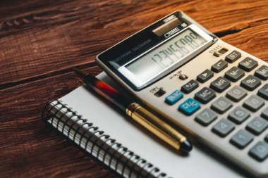 Hesap makinesinin ve kalemin defterdeki fotoğrafını kapat