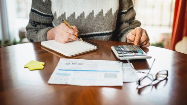 Kadın hesap makinesi kullanarak faturalarını hesaplıyor.