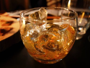 Koyu masada buzlu içki bardağı, sarı kehribar alkollü içecek. Viski, tek malt, brendi, rom, viski, konyak, burbon, alkol içeceği, barın arka planı
