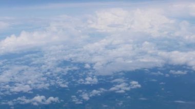 Beyaz kabarık bulutlar bir uçağın penceresinden görünüyor. Hava görüntüsü, yüksek irtifada bir uçakta uçmak, yüksek kaliteli görüntüler.