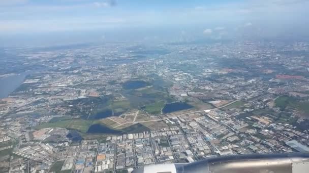 飛行機の窓からの壮大な緑の街の風景ビュー 空中ビュー 澄んだ空の昼 都市の風景 高高度で飛んで 高品質の映像 — ストック動画