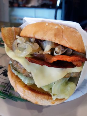 Tayland usulü lezzetli hamburgerleri et, pastırma, peynir, soğan ve buzdağının kıvrımlı kıvamında kıvırcık kıvırcık salatayı kağıt tabağa sarılmış beyaz kağıt, fast food, abur cubur