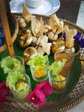 Çeşitli renkte Tayland yemeği ve muz yaprağı dokuma desenli pirinç çay standında, kızarmış, küçük pirinç bardakta çıtır çıtır, High Tea ya da ikindi çayı konsepti, Tayland tarzı gelenek