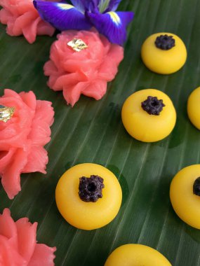 Çeşitli renkte Tayland tatlı çerezi. Muz yaprağının üzerinde. Pirinç desenli çay standında.