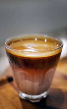 Yüksek açılı bir manzara ahşap masanın üzerinde bir bardak Dirty Coffee soğuk taze sütün üzerine espresso içmek kafe veya kahve dükkanında kirli, soğuk içecek menüsü denilen bir katman oluşturdu.