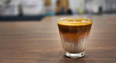 Yüksek açılı bir manzara ahşap masanın üzerinde bir bardak Dirty Coffee soğuk taze sütün üzerine espresso içmek kafe veya kahve dükkanında kirli, soğuk içecek menüsü denilen bir katman oluşturdu.