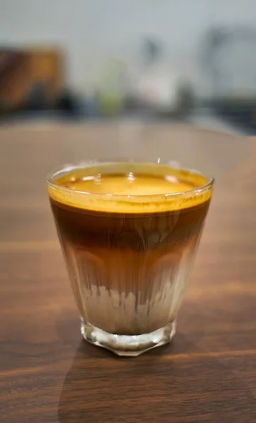 High angle view a glass of Dirty Coffee on wooden table, espresso shot over cold fresh milk created gradient layer called dirty, cold beverage menu in cafe or coffee shop