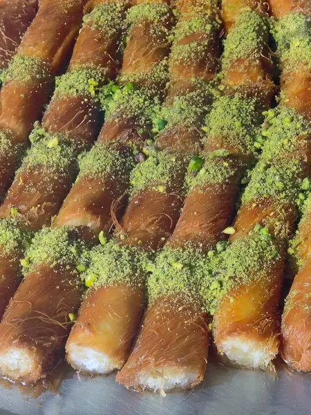 Fresh traditional pastries dessert sweet Baklava laying orderly rows in a tray for showcase, Arabian or middle east sweet with roasted Pistachio, street food at Petra Jordan, vertical image
