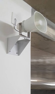 Bir elektronik korna hoparlörü ya da siren, megafon ya da hoparlör binanın beyaz duvarına asılarak kurulmuş, yayın, anons, bilgi, güvenlik sistemi konsepti