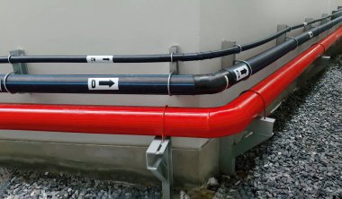 Bina duvarında asılı duran siyah ve kırmızı renkli yatay boru hattı mühendislik araç tasarım sistemini, inşaat sektörünü ve akış yönünü gösteriyor