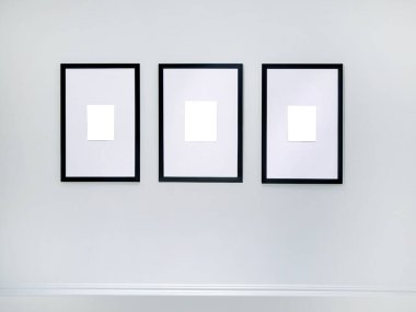 Beyaz duvarda asılı üç boş dikey resim çerçevesi, 3 posterden oluşan duvar sanatı modelleme seti, boş uzay çerçevesi modern iç mimari, kırpma yolu olan minimalist
