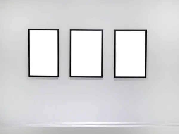 Three empty vertical picture frames hanging on white wall, Wall art mockup set of 3 posters, blank space frame modern interior style, minimalist with clipping path