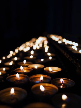 Küçük mum ışıkları, din kilisesinin karanlık arka planında ışık, erdem, dua, saygı, huzur ve din kavramını oluşturur.