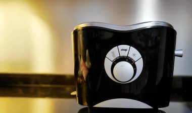 Modern siyah tost makinesi mutfakta, arka planda bulanık çekim, eğri tasarımı elektrikli ev aletleri, kahvaltı hazırlığı