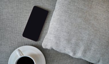 Flat Lay, Top view akıllı telefon modeli ve fotokopi alanı, dijital NOMAD, serbest çalışan işyeri veya online alışveriş konsepti olan kumaş tekstil üzerine bir fincan sade kahve.