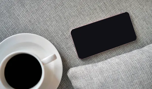 Flat Lay, Top view akıllı telefon modeli ve fotokopi alanı, dijital NOMAD, serbest çalışan işyeri veya online alışveriş konsepti olan kumaş tekstil üzerine bir fincan sade kahve.