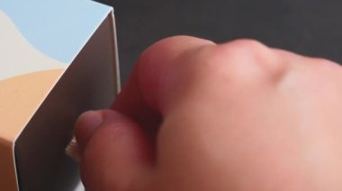 Görüntü, el, içinde süslü renkli badem kurabiyeleri gösteren küçük bir kutu, paket tasarımı, Fransız aperatifi, pasta tarifi, badem unu, badem kurabiyesi, koyu arkaplan 