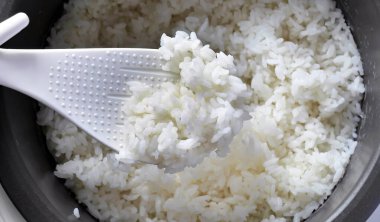 Beyaz kepçe üzerinde yumuşak Japon pilavı, lezzetli sıcak buhar pilavı, gıda endüstrisi, gıda sektörü, Asya tarzı sıcak yemek.