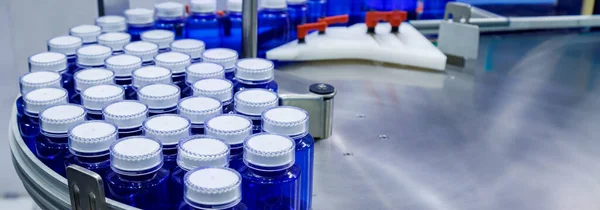 blue plastic bottle on production line of conveyor belt at filling machine in medical factory. pharmaceutical manufacturing.