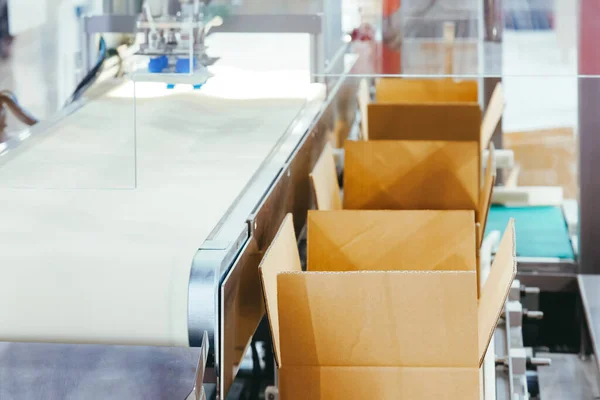 Karton kutu ürün ambalajı, imalat fabrikasındaki otomatik paketleme makinesinin taşıma bandıyla pazara dağıtıma hazır hale geliyor. lojistik üretim ve endüstriyel konsept.