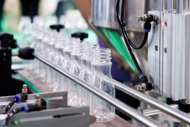 Temiz plastik içme suyu şişesi taşıyıcı bant ile içecek imalatında fabrika hattının doldurma makinesine hareket ediyor.