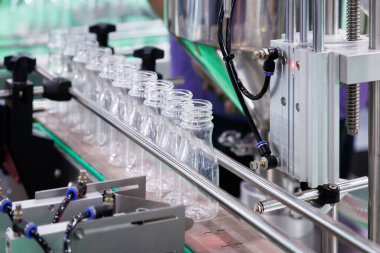 Temiz plastik içme suyu şişesi taşıyıcı bant ile içecek imalatında fabrika hattının doldurma makinesine hareket ediyor.