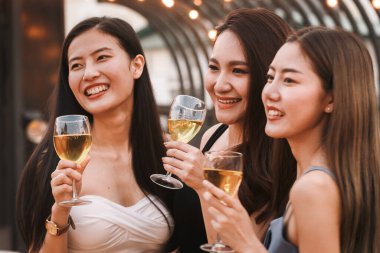 Bir grup Asyalı genç kız, yaz partisinde kutlama yapmak için beyaz şarap kadehiyle tezahürat yapıyor ve kadeh kaldırıyor. Kutlama, yıldönümü, doğum günü ve arkadaşlık kavramı.