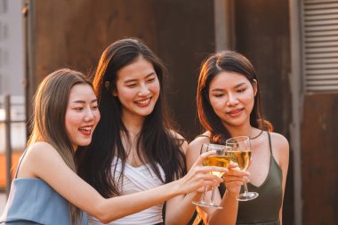 Bir grup Asyalı genç kız, yaz partisinde kutlama yapmak için beyaz şarap kadehiyle tezahürat yapıyor ve kadeh kaldırıyor. Kutlama, yıldönümü, doğum günü ve arkadaşlık kavramı.