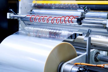 Gıda ürünleri fabrikasındaki otomatik paketleme makinesinde plastik ambalaj filmi. sanayi ve teknoloji kavramı.