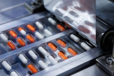 Kaliteli ilaç fabrikasının otomatik kapsül dolum makinesinde paketleme işleminde alüminyum folyo ambalajı için kapsül hapı hazır. tıbbi endüstriyel ve imalat kavramı