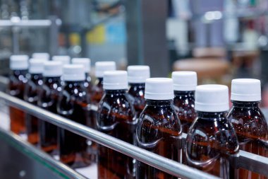 glass bottle with white cap moving on conveyor belt of auto capping and labeling machine at energy drink beverage manufacturing. pharmaceutical or beverage industry. automation technology machinery. clipart