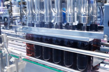 Enerji içeceği imalatında otomatik kaplama ve etiketleme makinesinin konveyör bandı üzerinde hareket eden cam şişesi. İlaç ya da içecek endüstrisi. otomasyon teknolojisi makineleri.