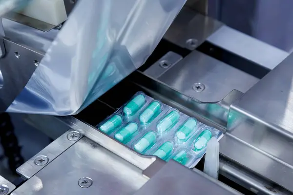 Kaliteli ilaç fabrikasının otomatik kapsül dolum makinesinde paketleme işleminde alüminyum folyo ambalajı için kapsül hapı hazır. tıbbi endüstriyel ve imalat kavramı
