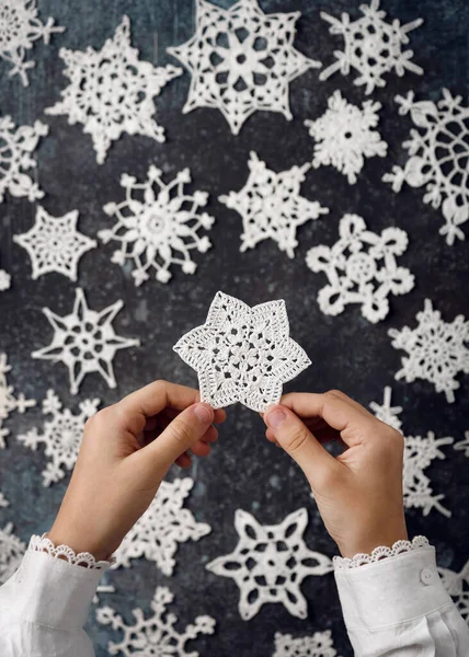 One of beautiful white cotton crocheted star snowflakes in girls hands as a small handmade gift or home decoration. Christmas DIY concept. Top view.