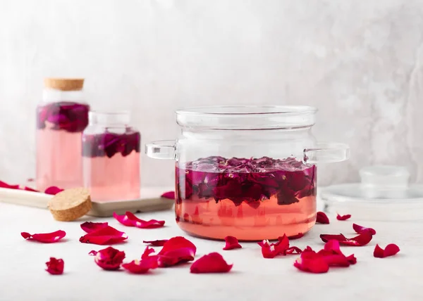 stock image Homemade rose syrup in a glass pot with pink organic petals for making lemonade, cocktail, sweet summer drinks. Healthy food concept. Selective focus.