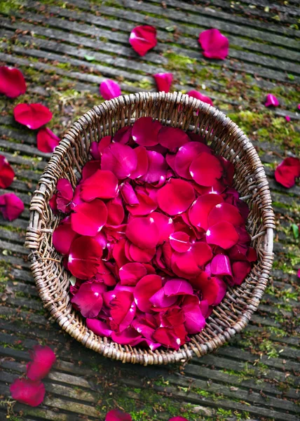 シロップ エッセンシャルオイル デザート 乾燥や結婚式の装飾の準備のための庭で新鮮に選ばれた赤いバラの花びらを持つウィッカーバスケットのトップビュー 素朴な様式 — ストック写真