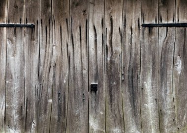 Yıpranmış eski gri ahşap kapılı ve metal parçaları dövülmüş. Rustik stil. Boşluğu kopyala.