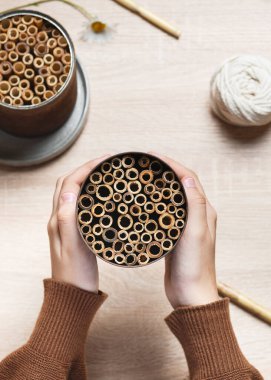 Altıncı adım. Bambu çubuklu dolu teneke kutulu çocuk elleri. Bahçe için DIY böceği oteli oluşturun. Çocuklar vahşi hayvan kavramını geliştirir ve ona yardım eder.